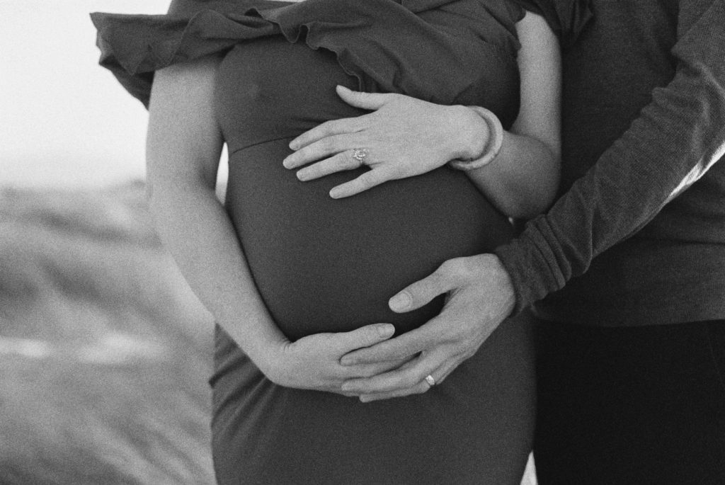 Film photo of couple with their hands on woman's pregnant belly