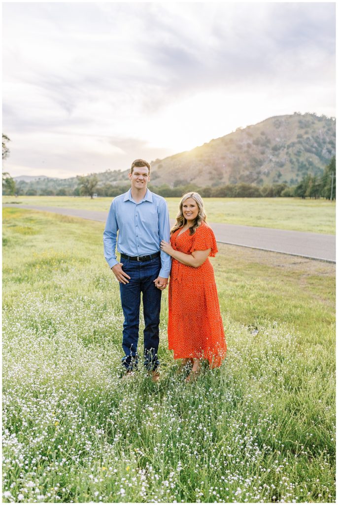 Engaged couple standing in the wildflowers with a mountain behind them for engagement photos