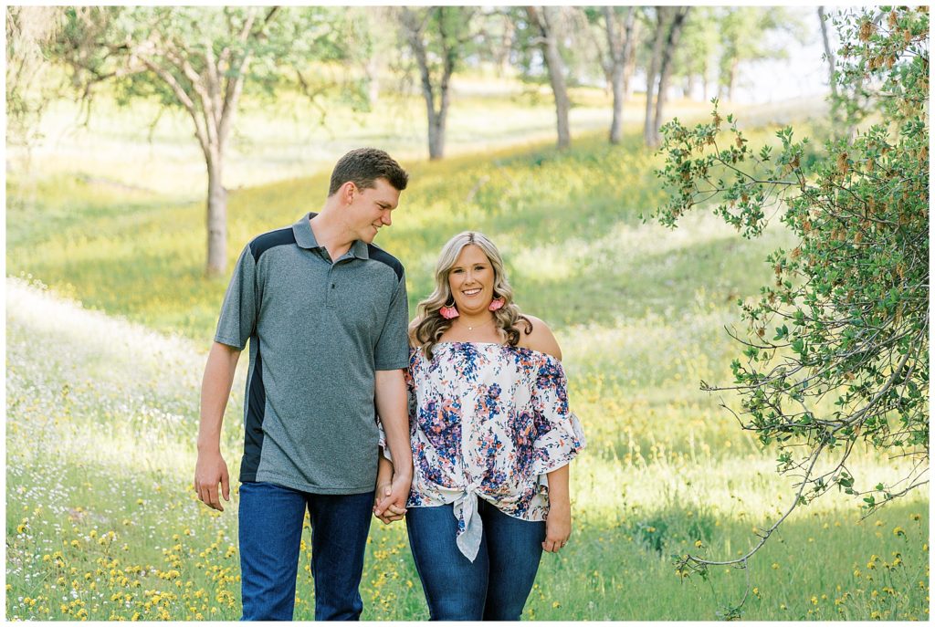 Couple holding hands and walking among the wildflowers for engagement photos
