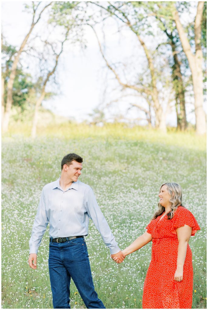 Man leading woman through a field of wildflowers for engagement photos