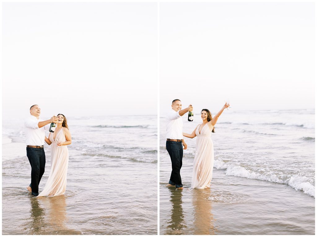 Couple popping champagne while standing in the ocean 