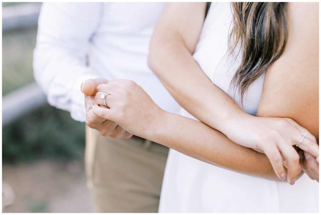 People holding hands with woman's engagement ring in focus