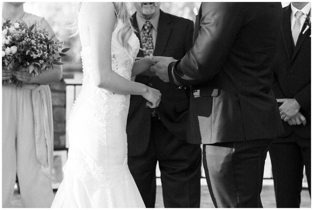 black and white photo of groom placing wedding ring on brides finger