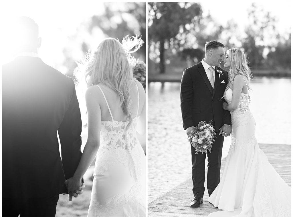 black and white photo of a bride and groom walking and embracing on a dock by the lake