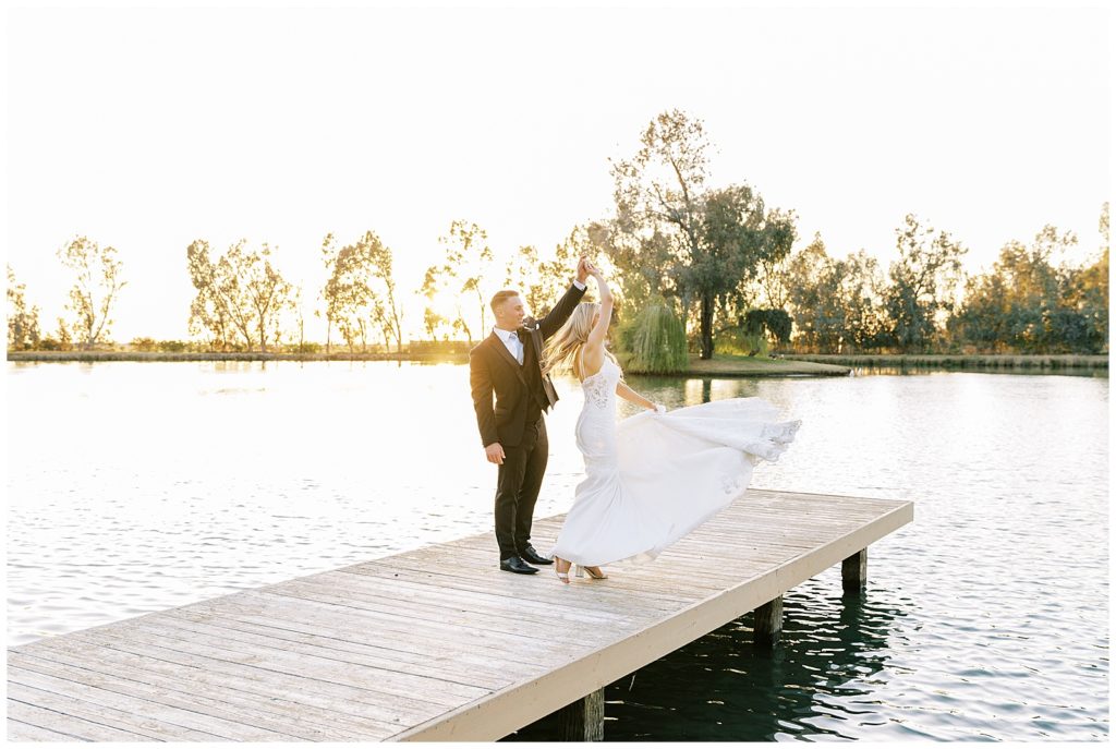 bride twirling in wedding dress on dock at wolf lakes park at sunset