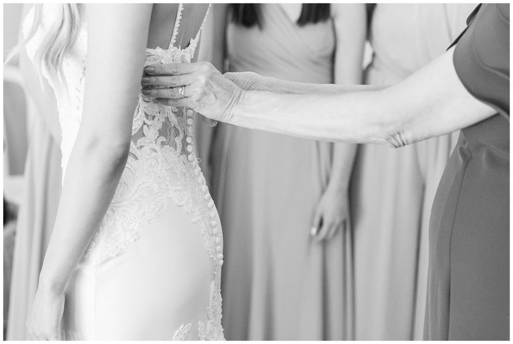 black and white photo of mom helping button a brides wedding gown