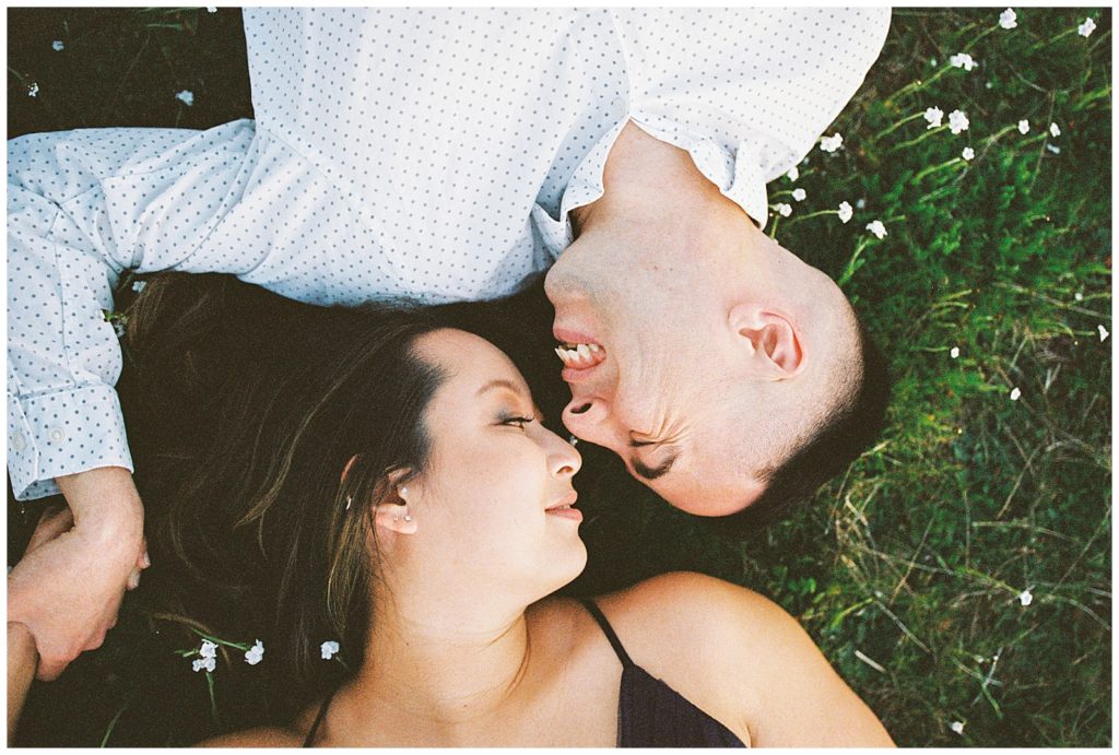 Couple laying in the grass at Lost Lake holding hands and laughing