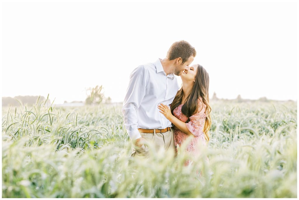 Coup[le kissing in a wheat field in spring during engagement