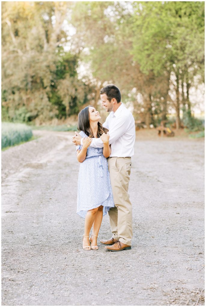 Man hugging fiance in a dirt road during spring engagement