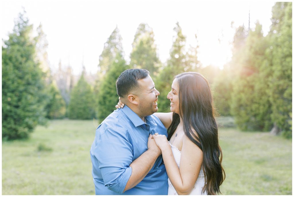 engaged couple dancing in a meadow during golden hour while smiling and laughing
