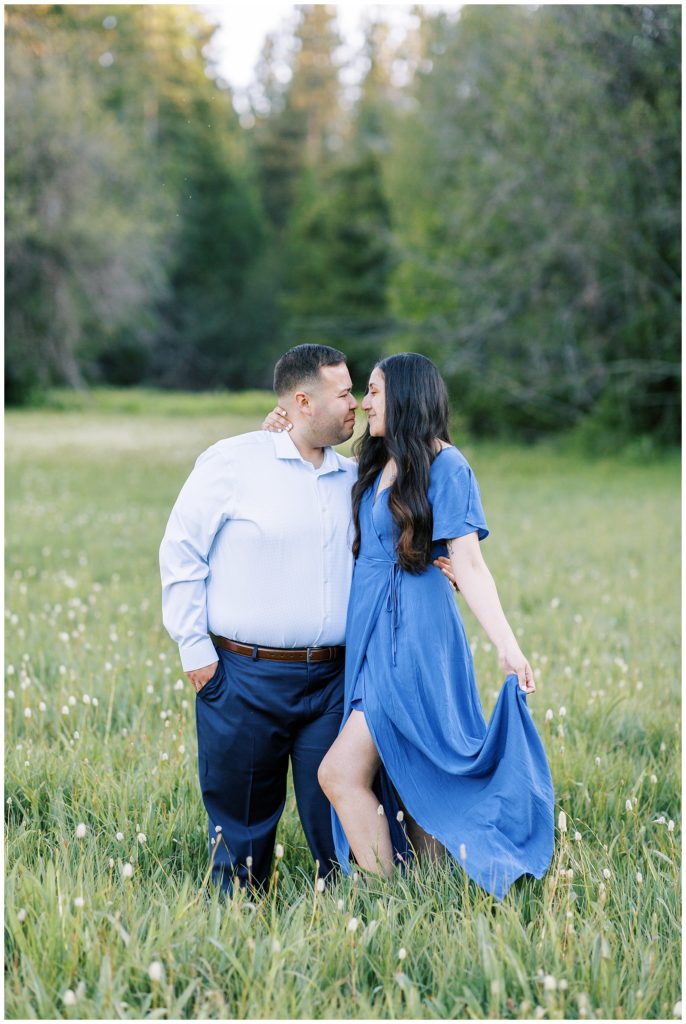 engaged couple wearing blue embracing in a meadow