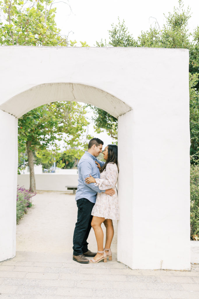 engaged couple embracing against a stone wall in downtown monterey
