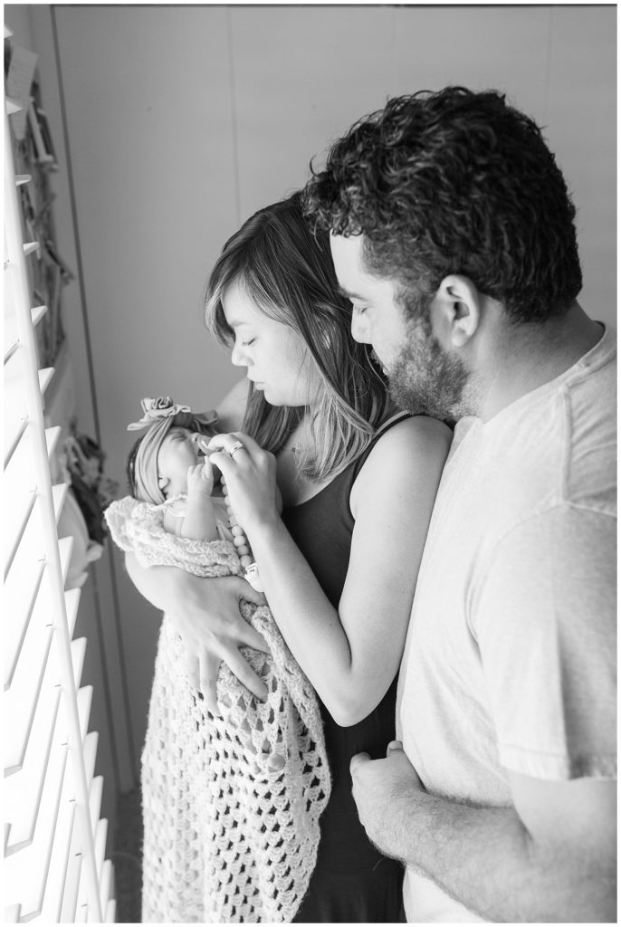 black and white photo of mom and dad soothing newborn baby girl