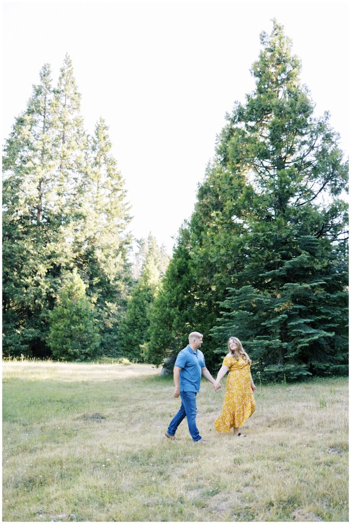 woman and man holding hands walking through grassy mountain meadow shaver lake