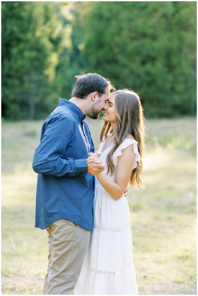 engaged couple dancing in meadow and kissing