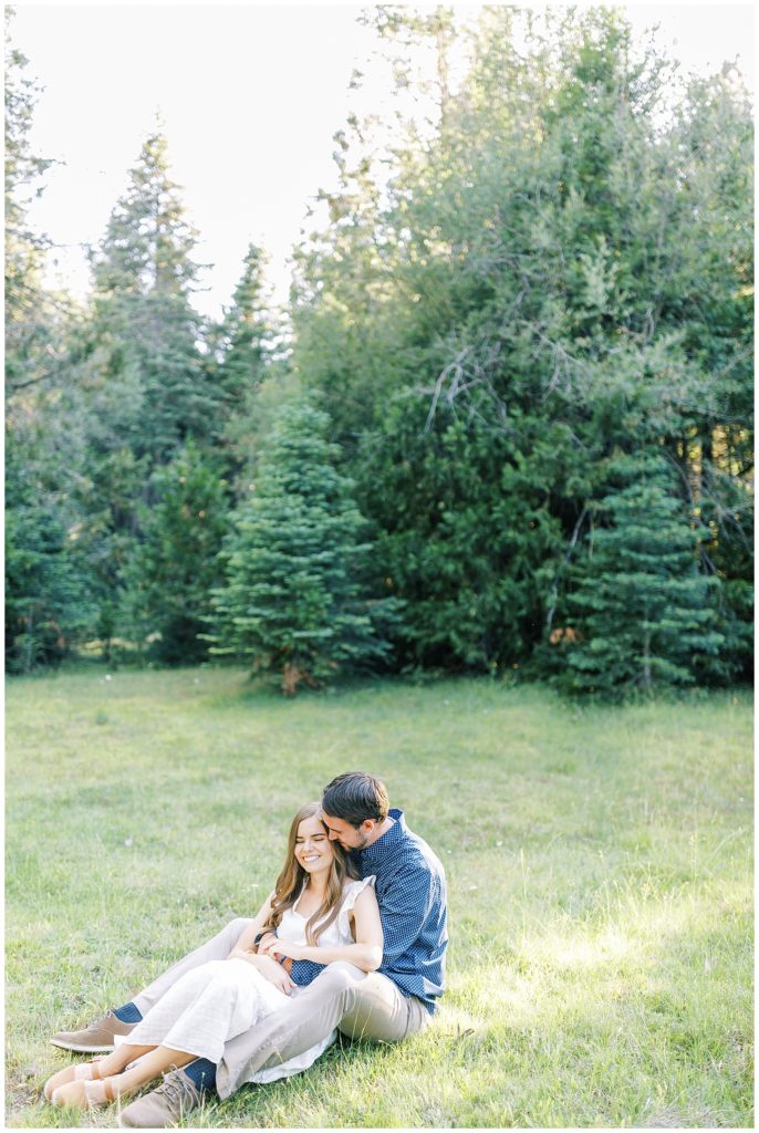 couple cuddling and sitting in grass in mountain meadow in shaver lake