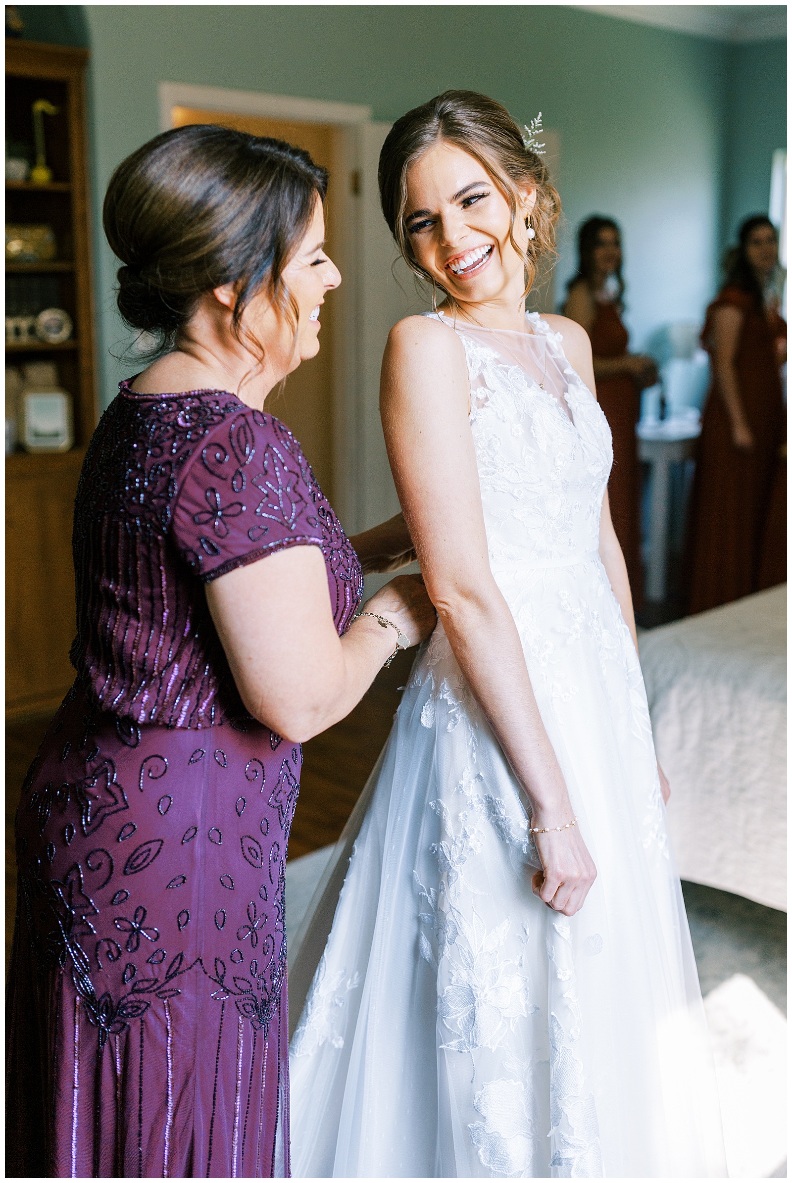 bride smiling at mom as mom buttons wedding gown bride getting ready