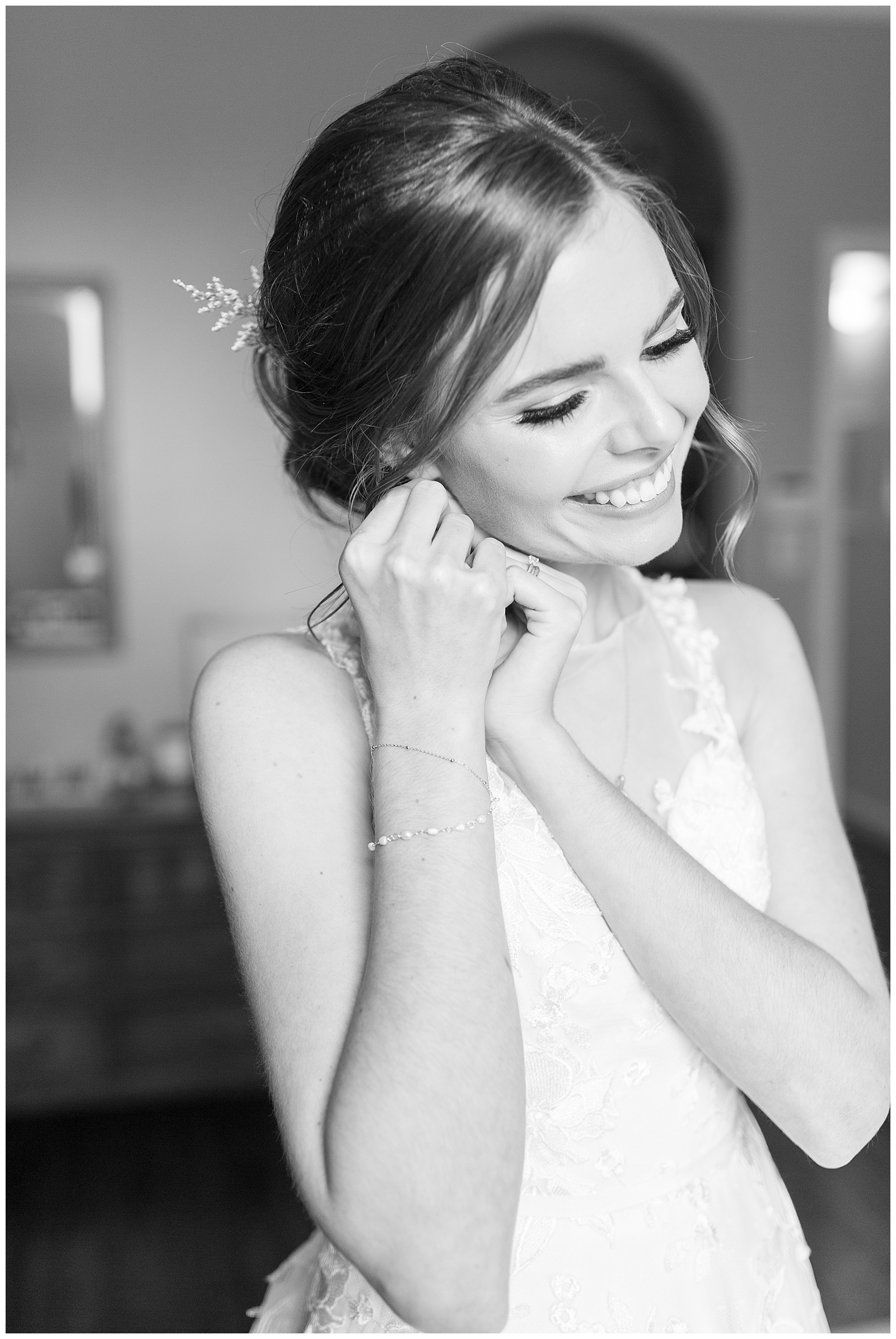 close up black and white image bride smiling putting earrings in on wedding day getting ready photos by frenso wedding photographer megan helm photography