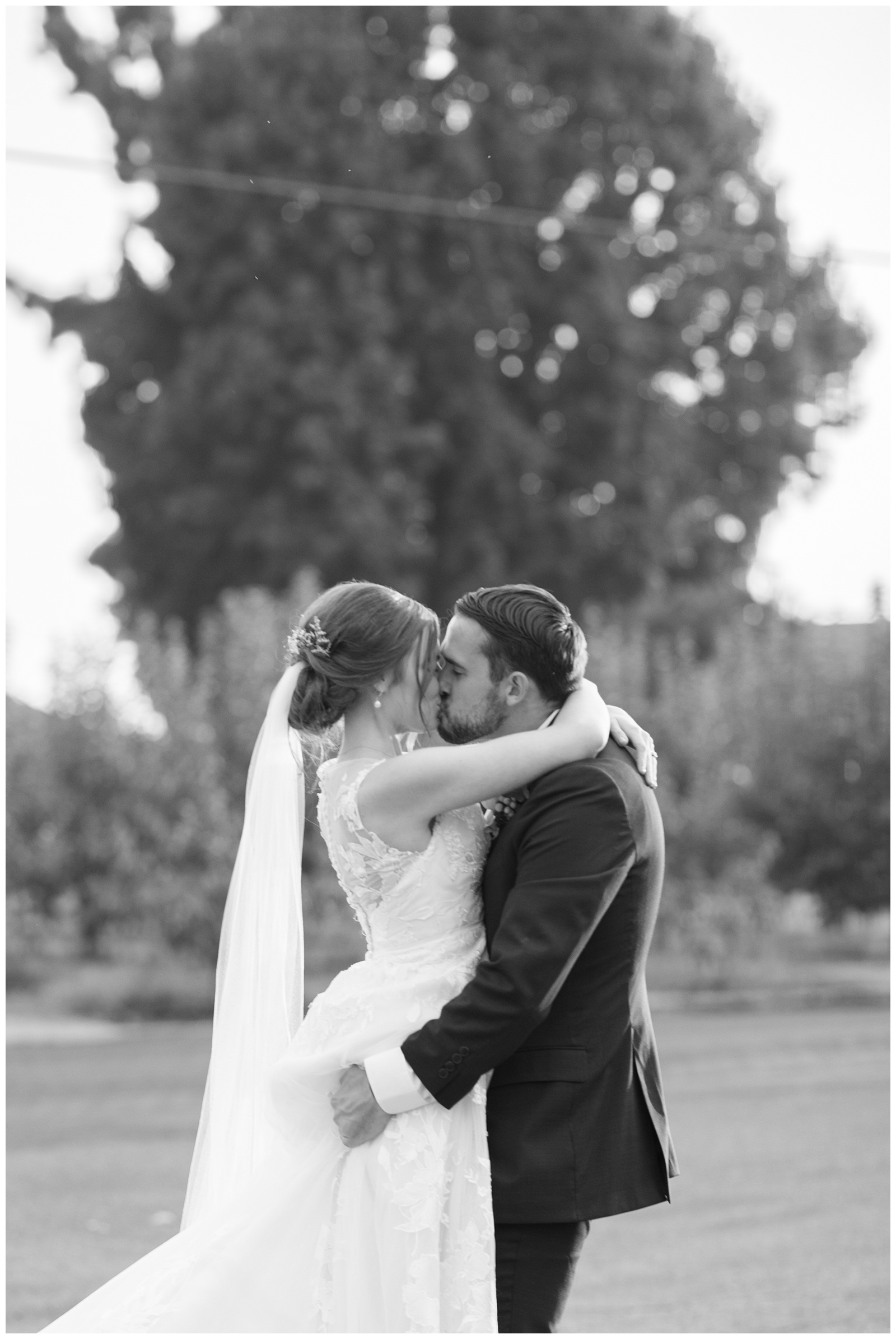 groom picking bride up and kissing her black and white image