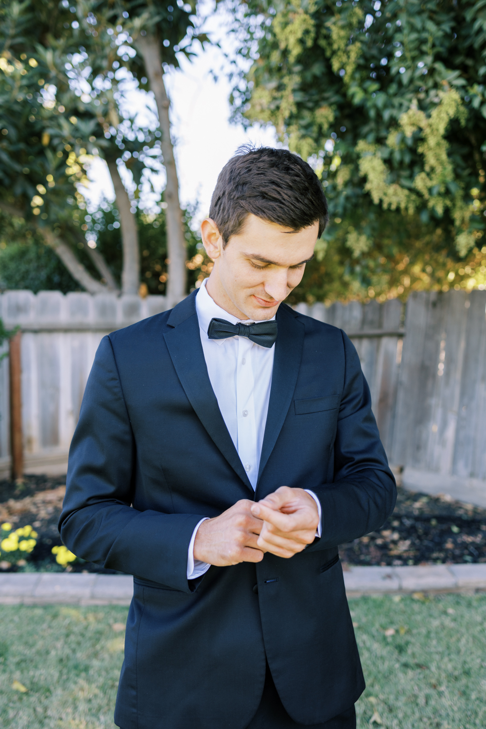 groom in black suit adjusting cuff links
