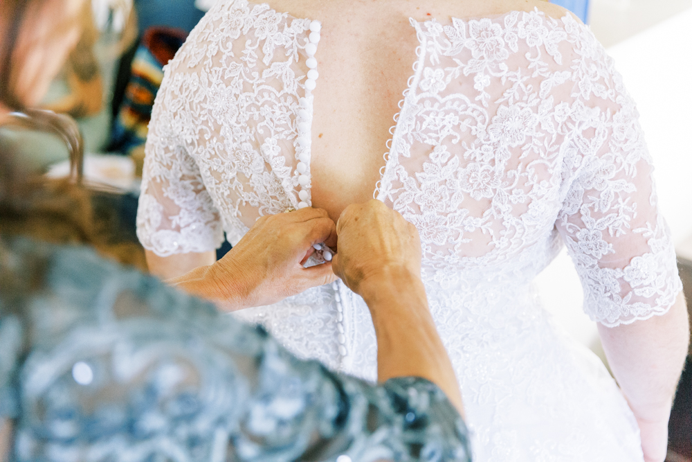mom buttoning brides wedding dress