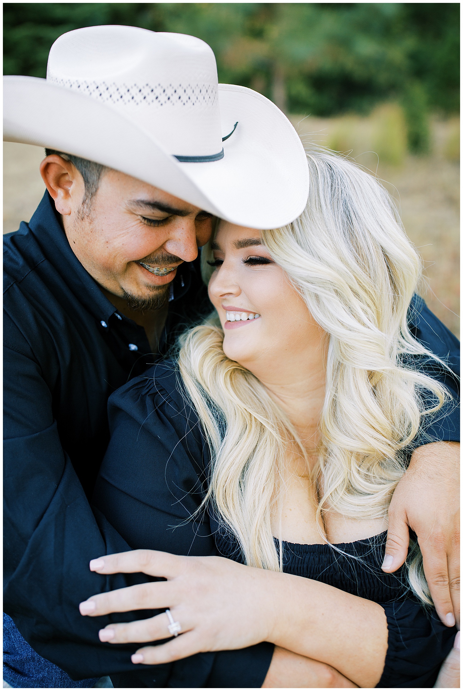 engaged couple embracing man wearing cowboy hat black shirt