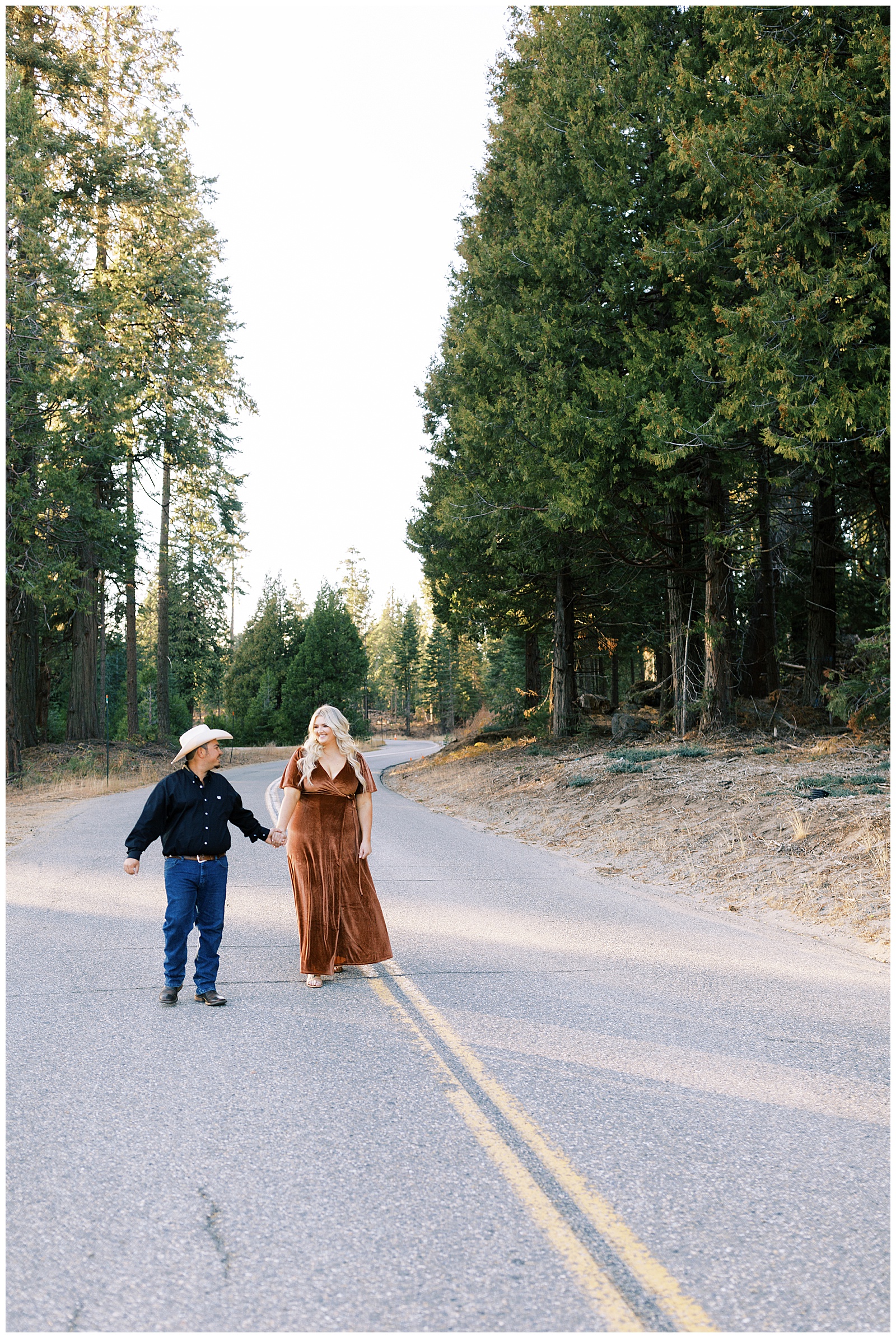 man and woman holding hands walking along mountain road shaver lake engagement photos