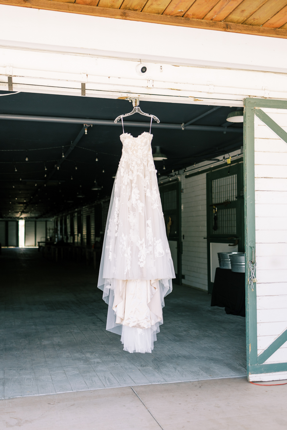 floral lace wedding dress hanging on white barn doorway springville ranch wedding