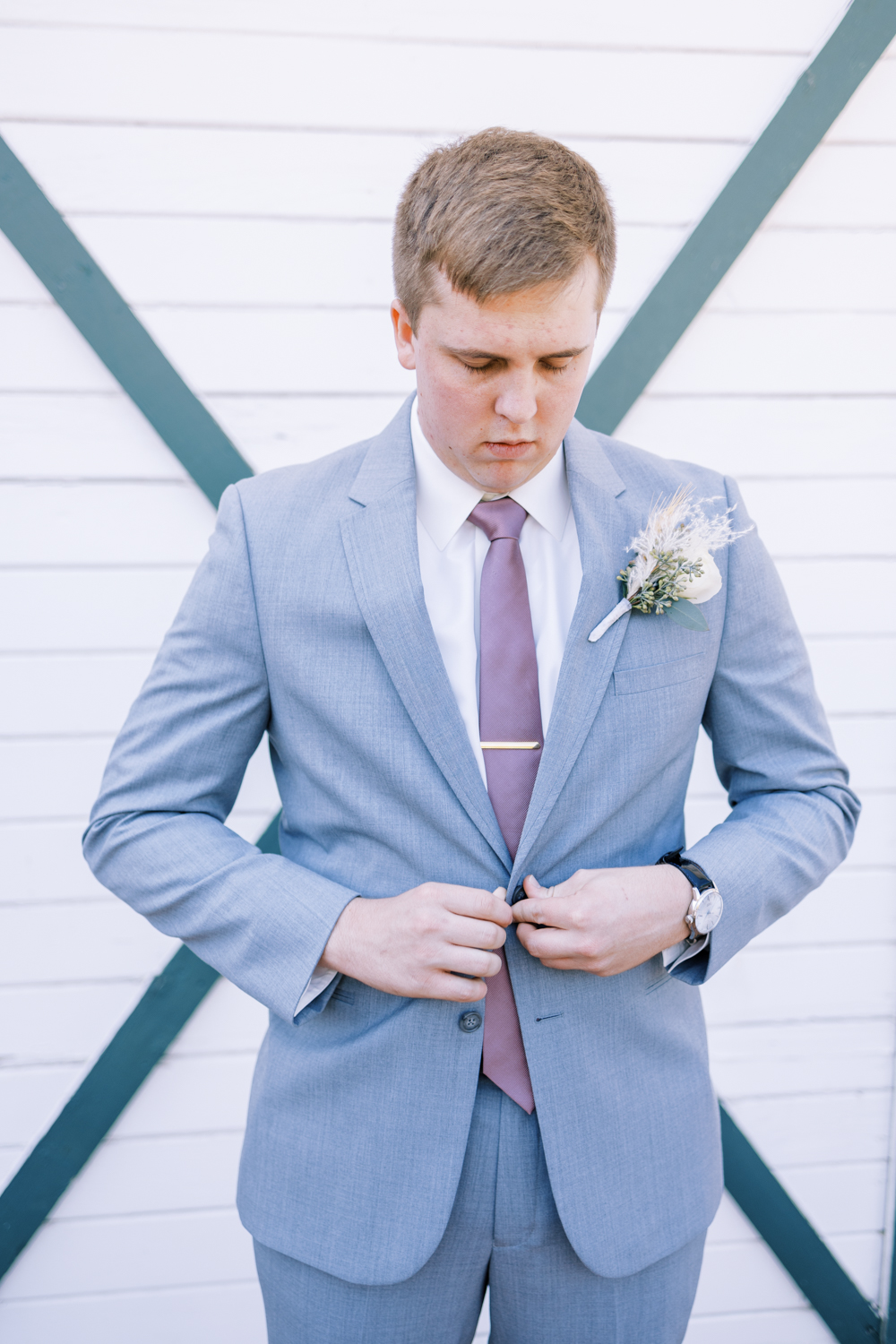 groom buttoning grey suit jacket
