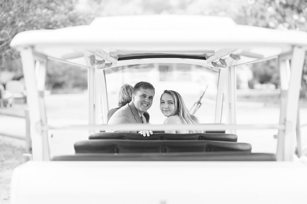 black and white photo bride and groom looking behind them on golf cart