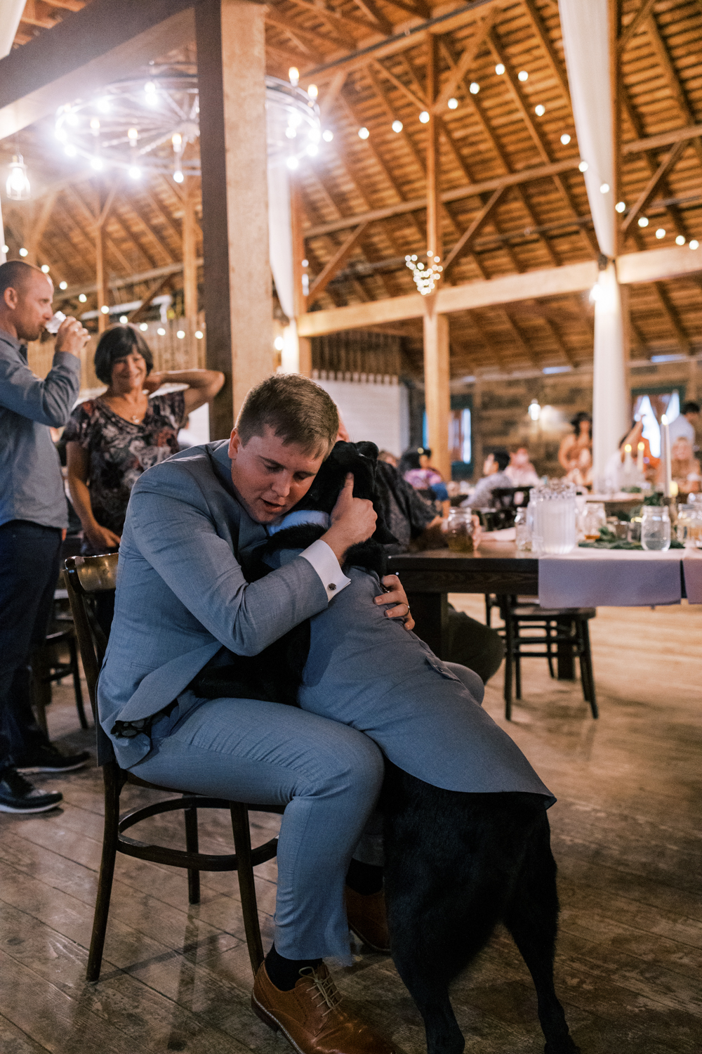 groom hugging his dog at wedding reception