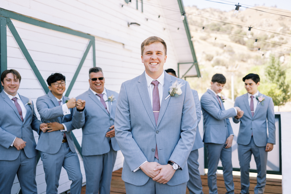 groom smiling with groomsmen behind him