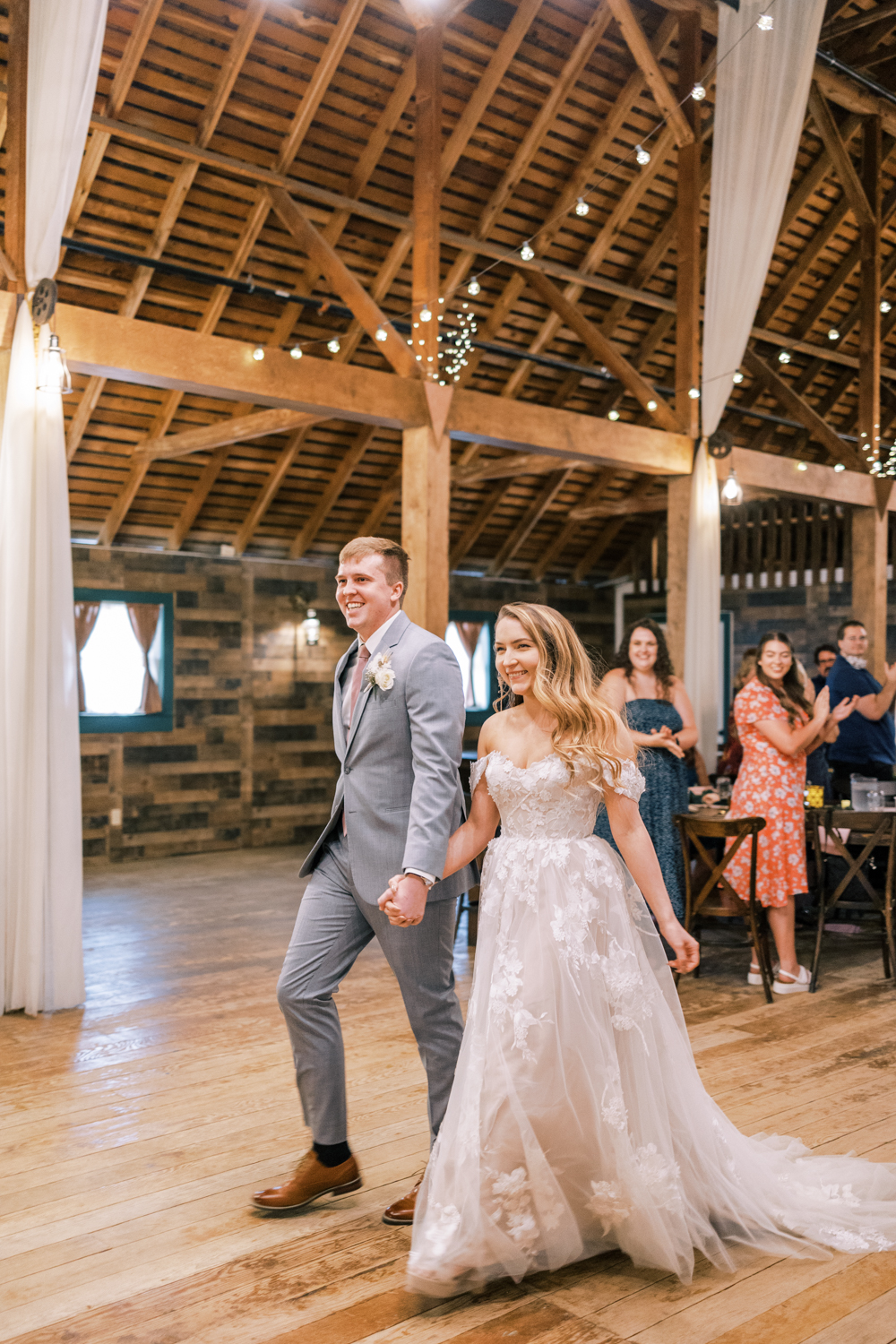 bride and groom holding hands and walking into springville ranch wedding reception in a barn