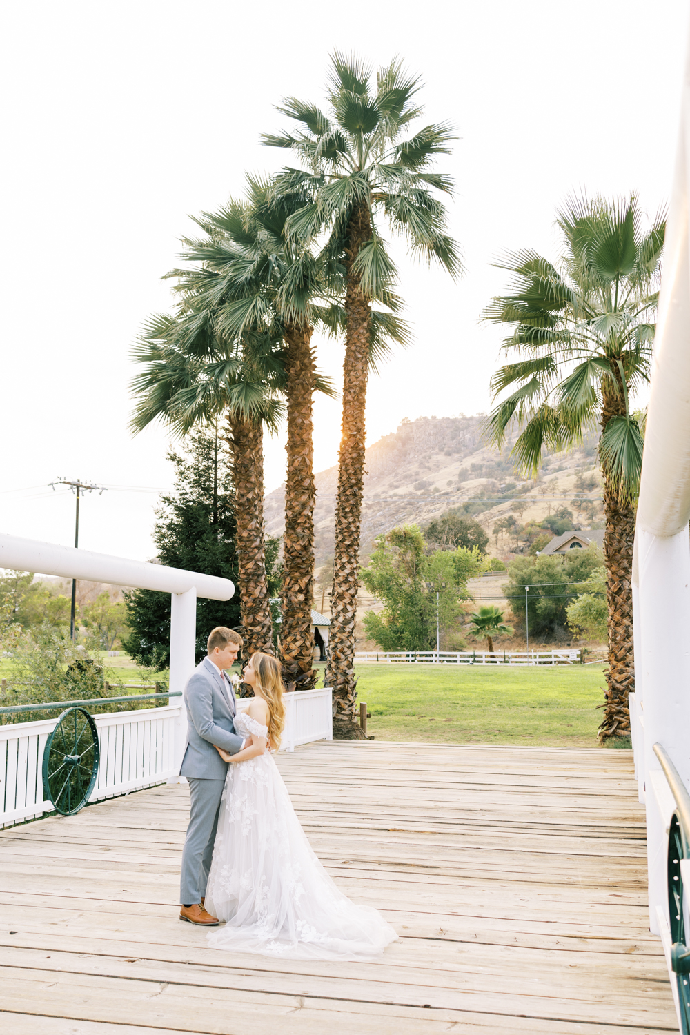 bride and groom embracing with palm trees and glowing sunset behind them springville ranch wedding