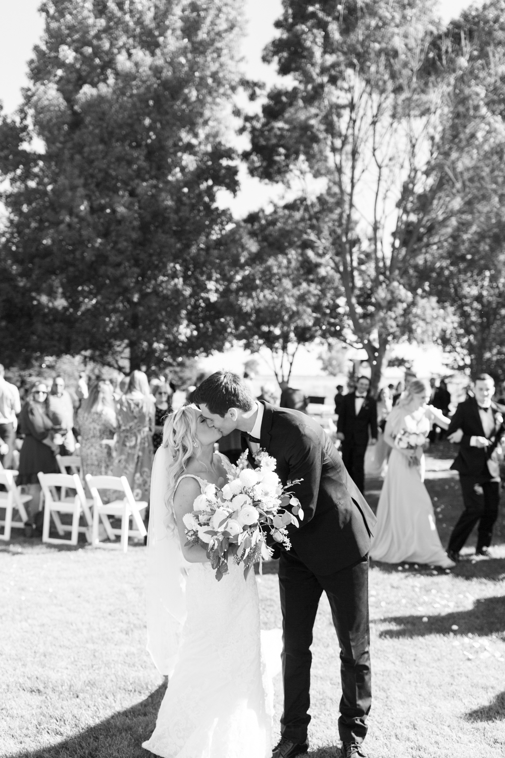 bride and groom kissing at end of aisle after wedding ceremony black and white photo elegant backyard wedding photos