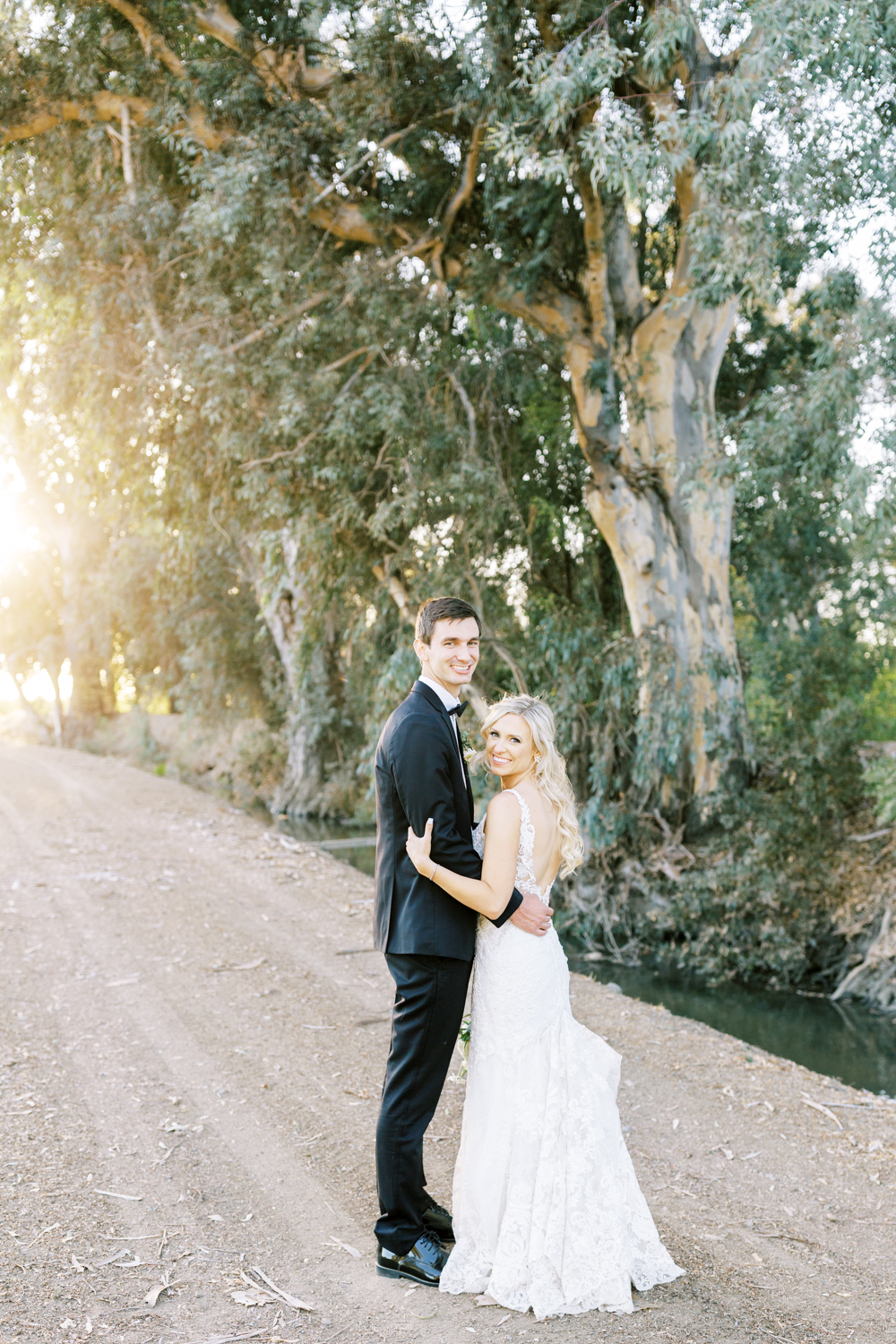 bride and groom smiling along eucalyptus lines drive