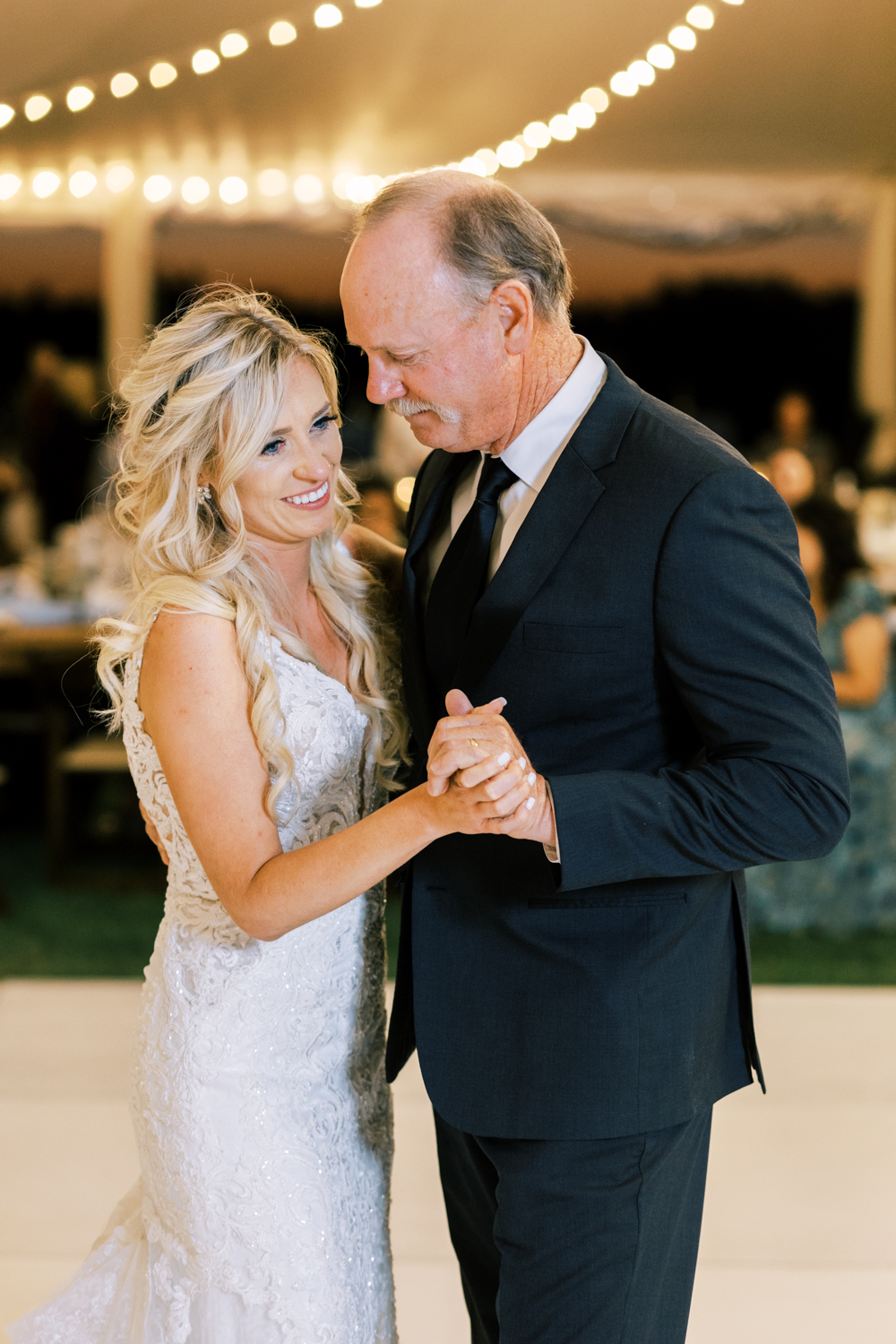 bride dancing with her father under tent at wedding reception emotional