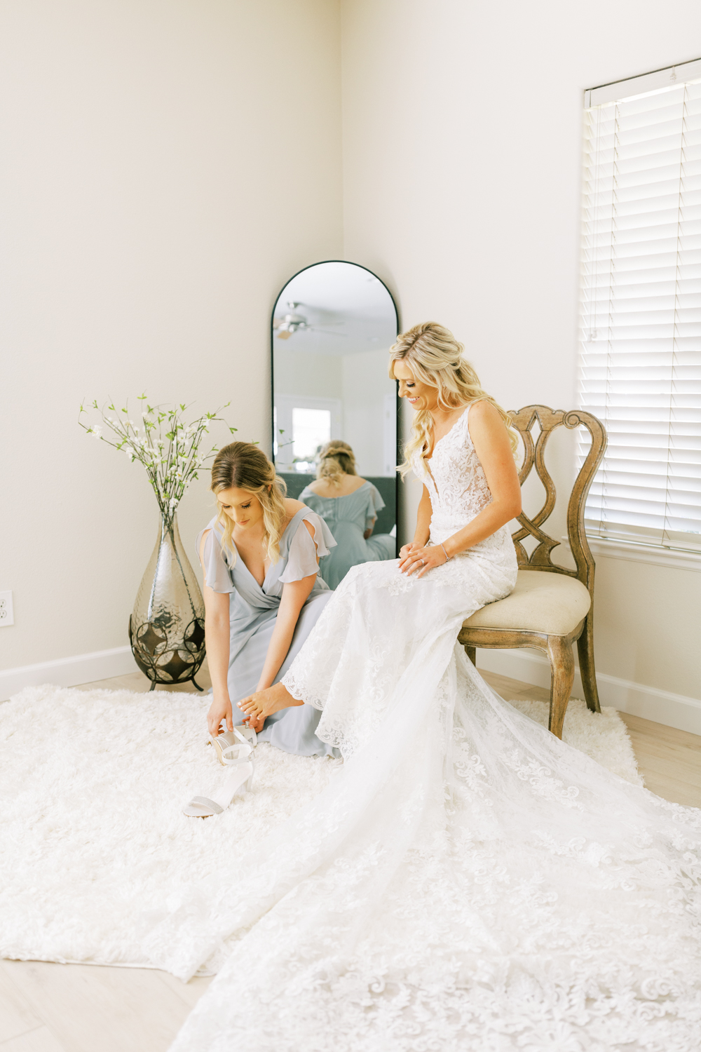 maid of honor helping bride put on wedding shoes