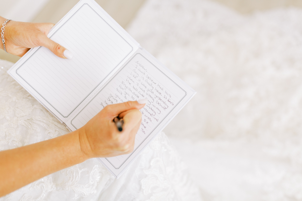 bride writing wedding vows in vow book