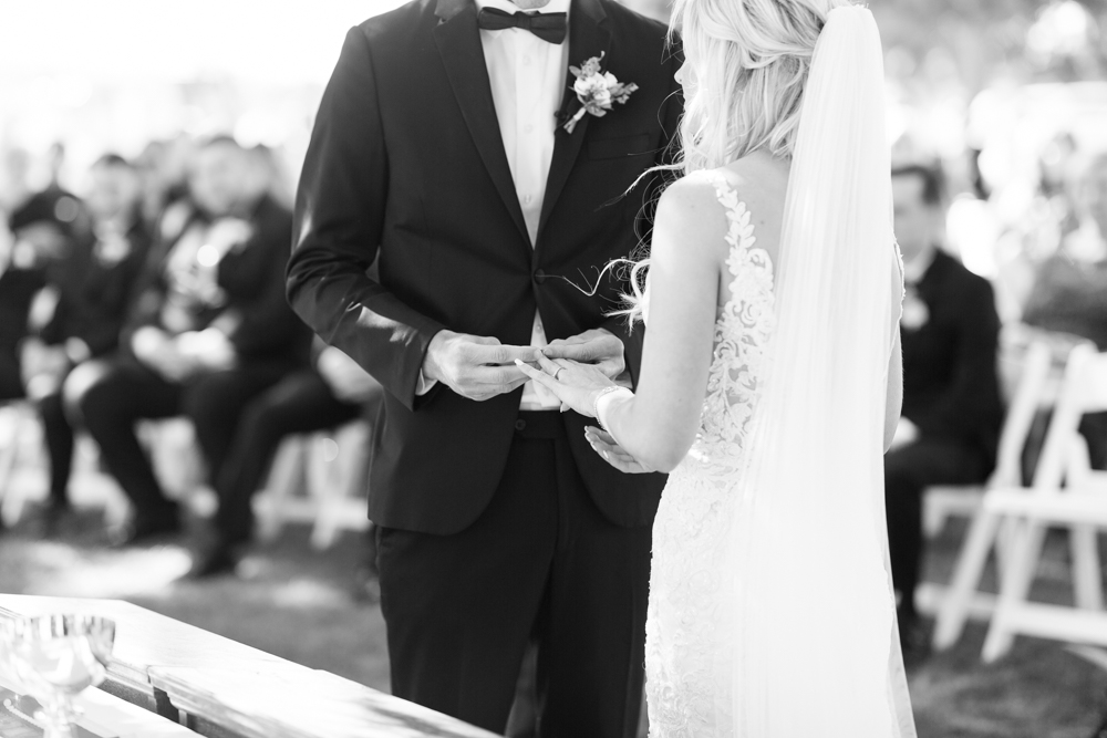 groom placing wedding ring on brides finger black and white