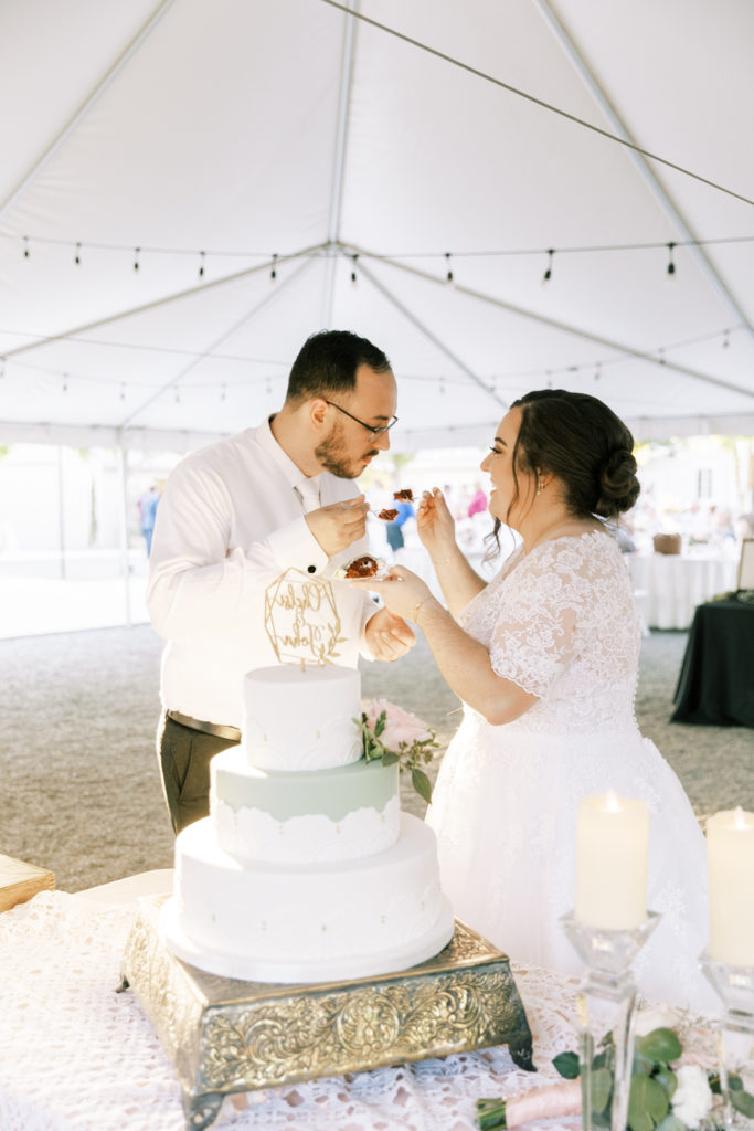 bride and groom feeding eachother wedding cake