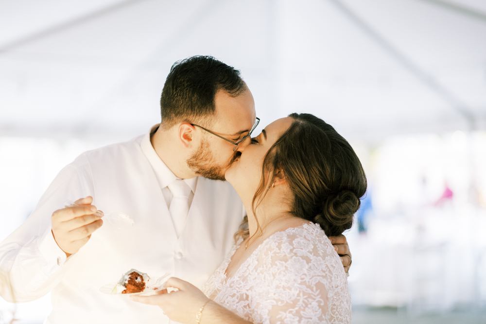 bride and groom kissing after cutting wedding cake