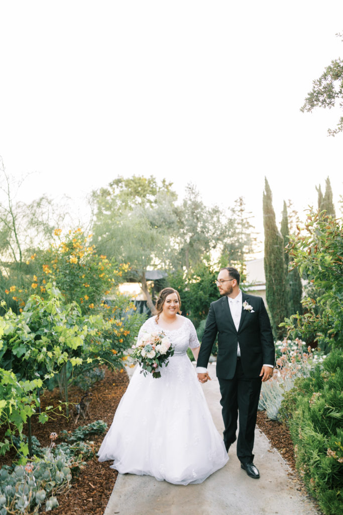 bride and groom holding hands and walking though the gardens venue wedding venue tulare california