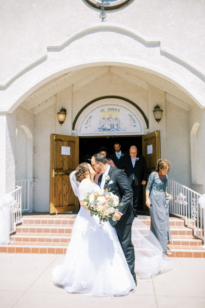 bride and groom kissing outside church after wedding ceremony