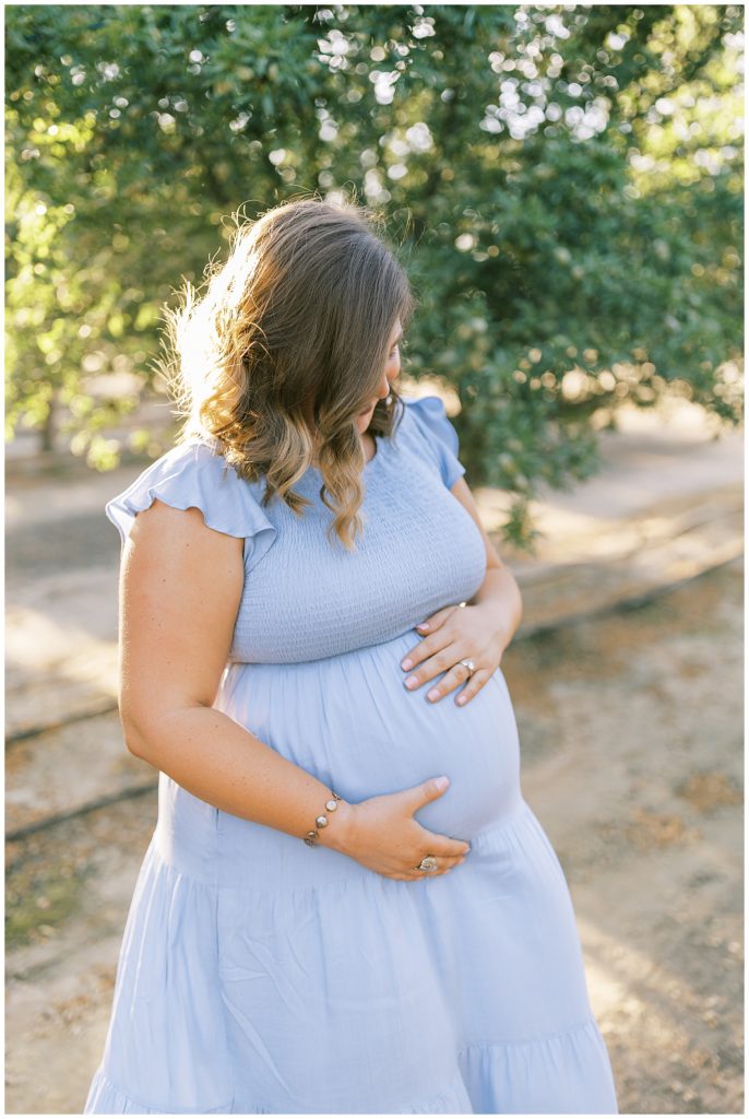 pregnant woman in blue dress holding baby belly 