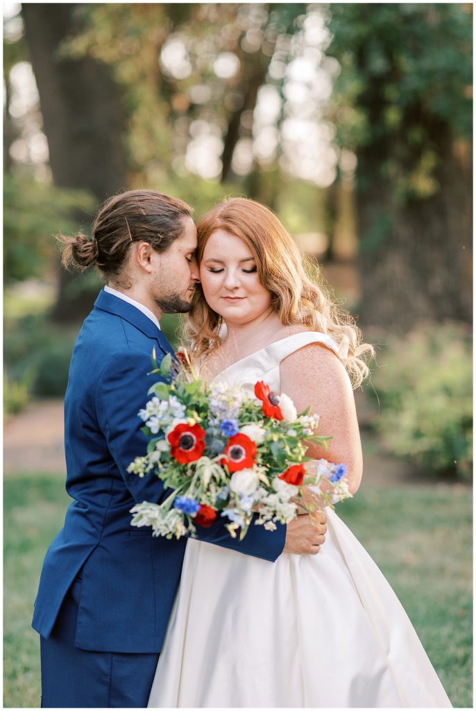 bride and groom arms around each other with red white and blue wedding flowers