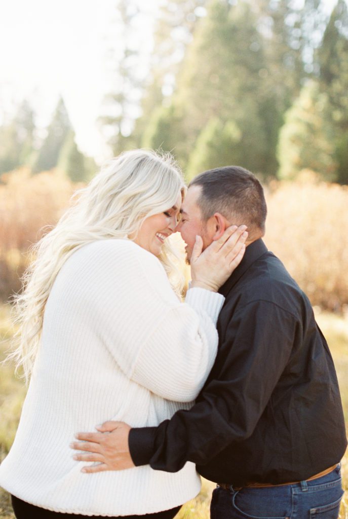 man and woman embracing leaning in for a kiss fall shaver lake engagement photos