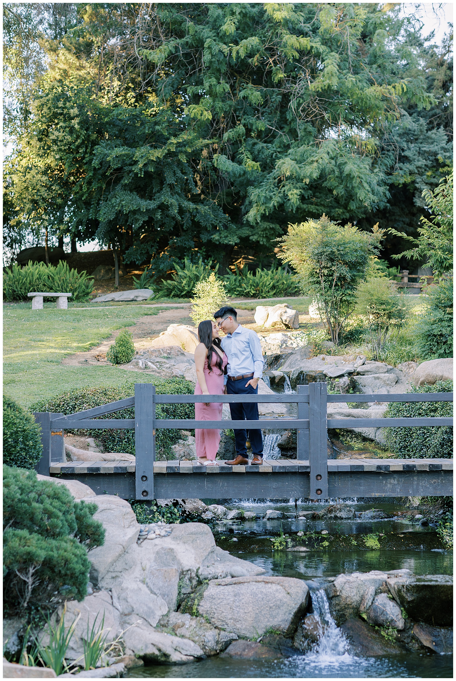 engaged couple embracing on bridge over waterfall at shinzen japanese gardens