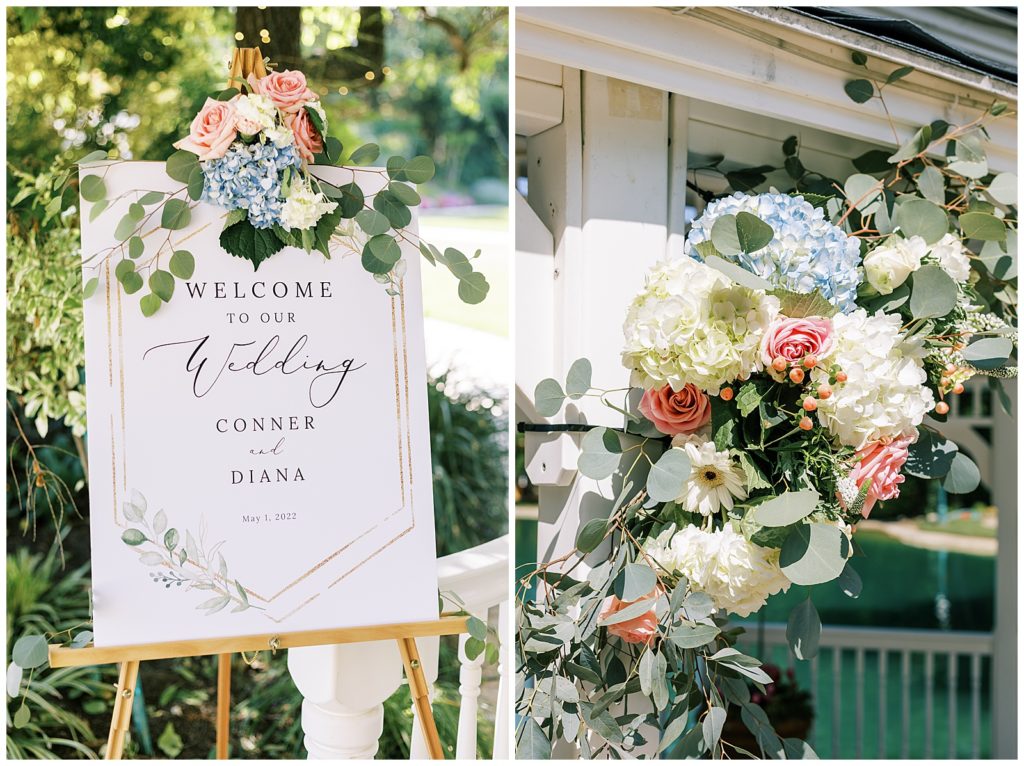 wedding florals with blue hydrangeas and pink roses with eucalyptus leaves decorating white and gold wedding welcome sign