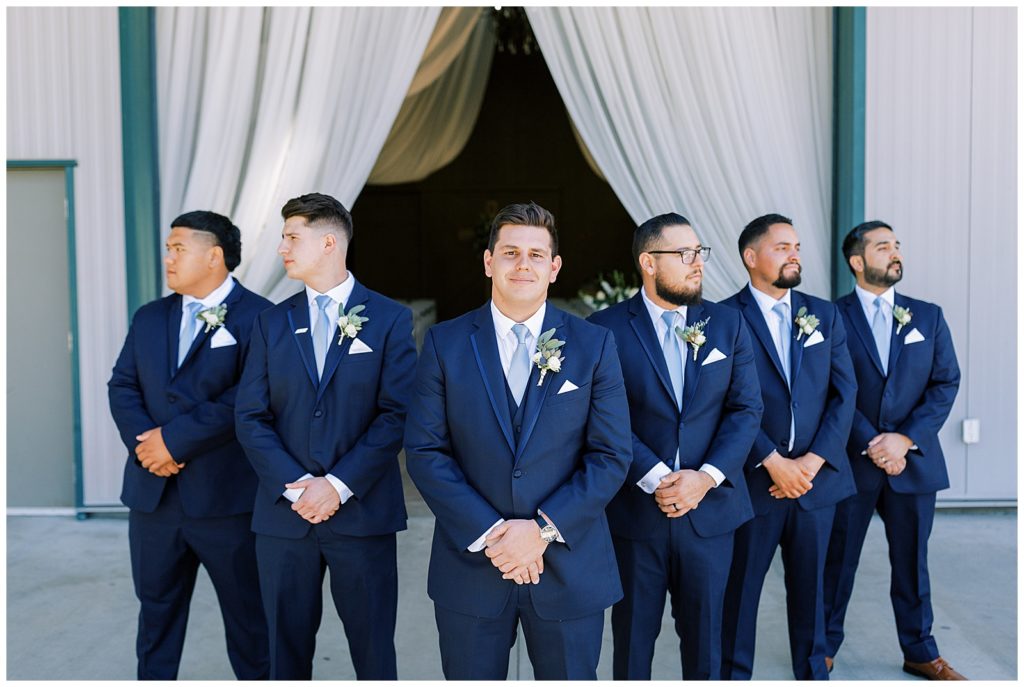 groom and groomsmen in flying v pose wearing navy blue suits at kings river winery